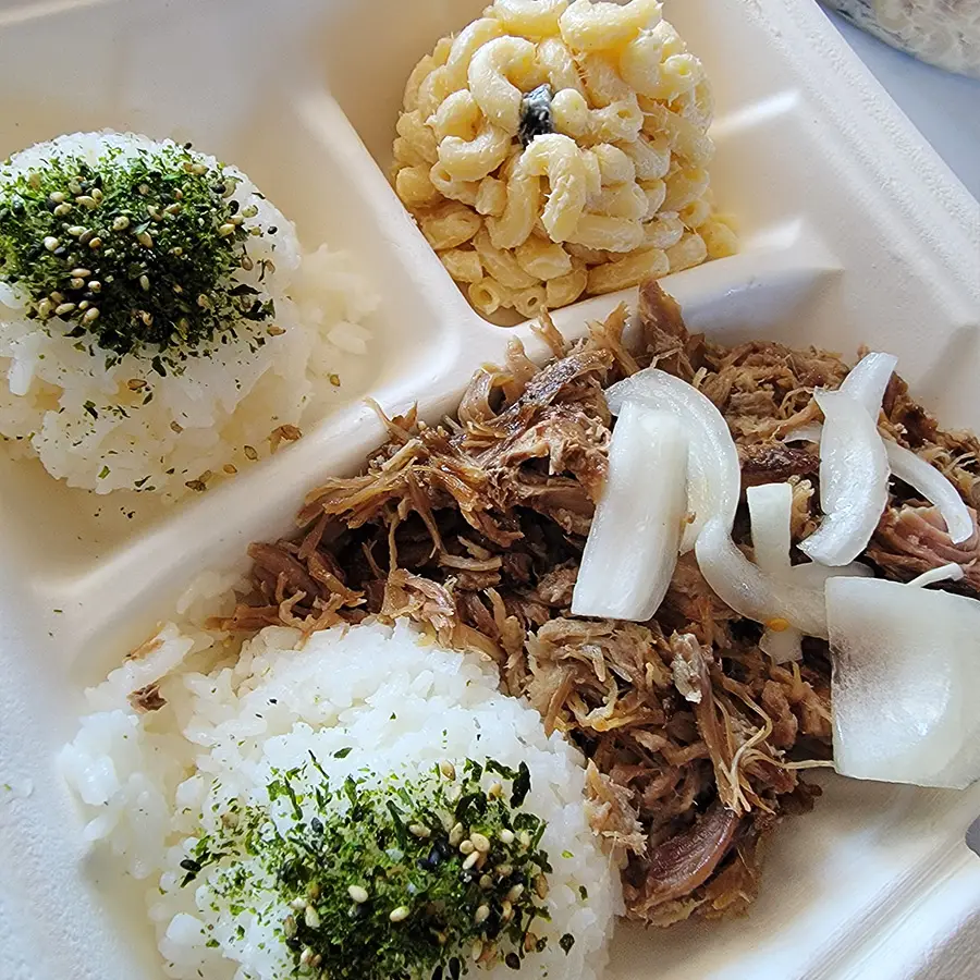 Hawaiian plate lunch featuring pulled pork, two rice servings topped with furikake, and a scoop of macaroni salad.