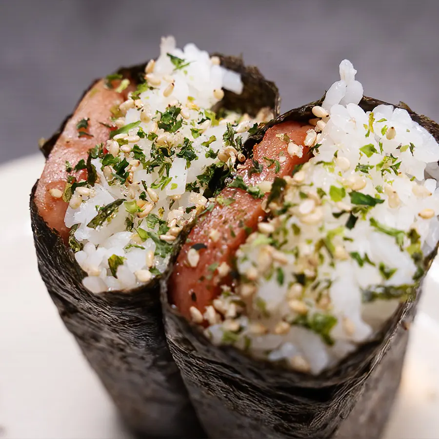 Close-up of two musubi pieces with rice, spam, seaweed, and furikake seasoning, representing Hawaiian cuisine from Pua's Plate Lunch.