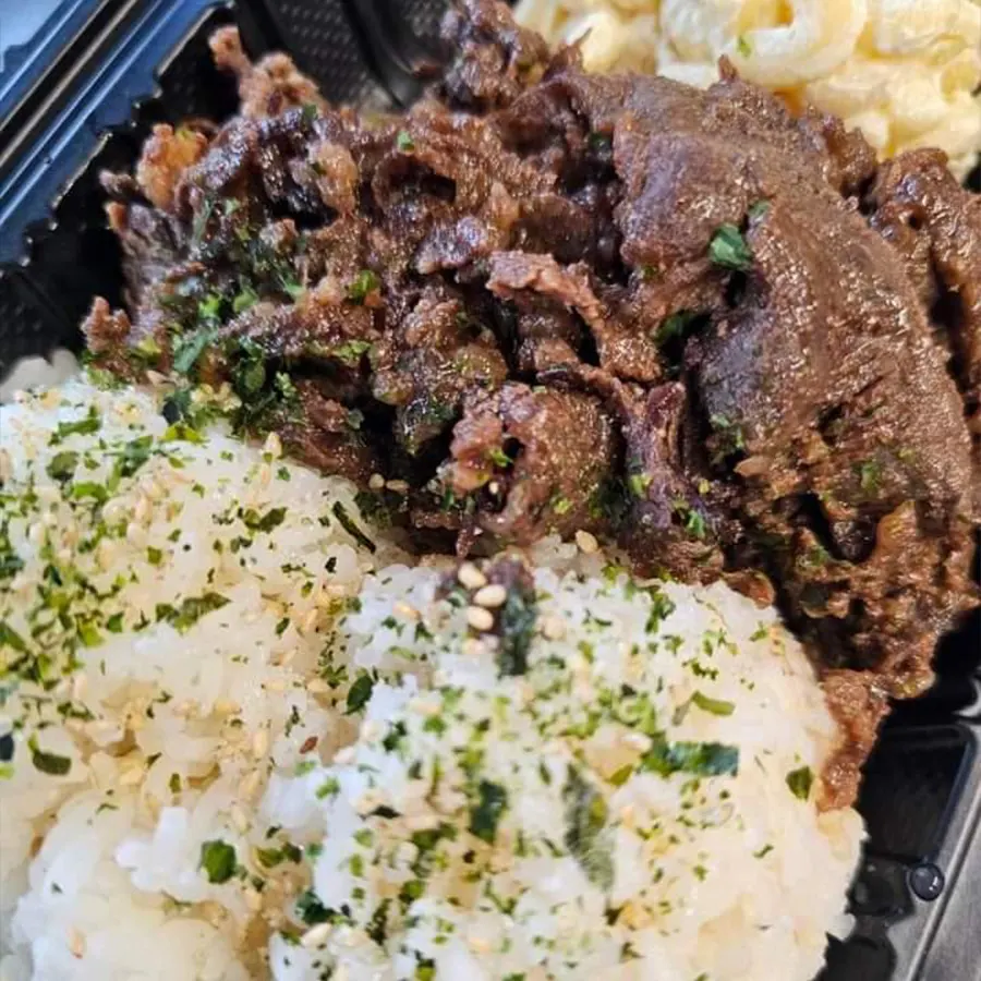 Beef plate lunch with rice topped with furikake and creamy macaroni salad, representing Hawaiian cuisine by Pua's Plate Lunch.