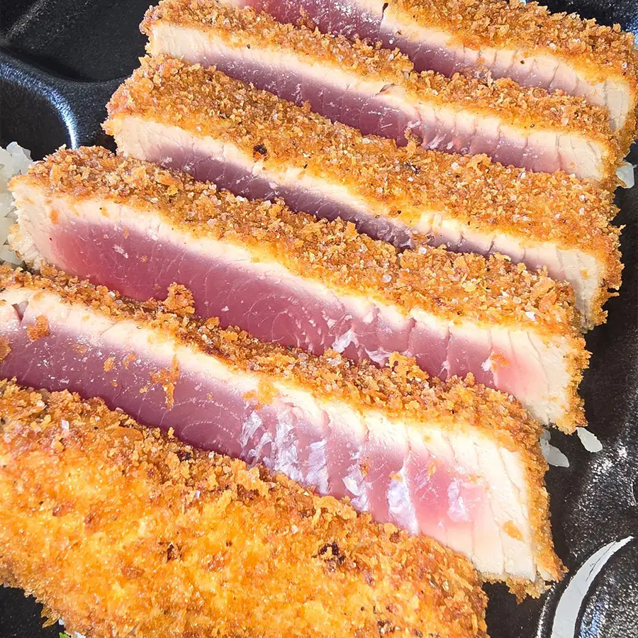 Crispy, golden-brown slices of seared ahi tuna with a breadcrumb crust, exemplifying Hawaiian cuisine from Pua's Plate Lunch catering.